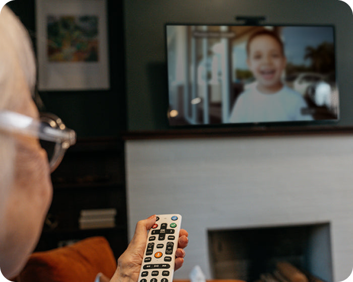 elderly woman holding the jubileetv remote for seniors, looking at a photo of her young grandson on her television
