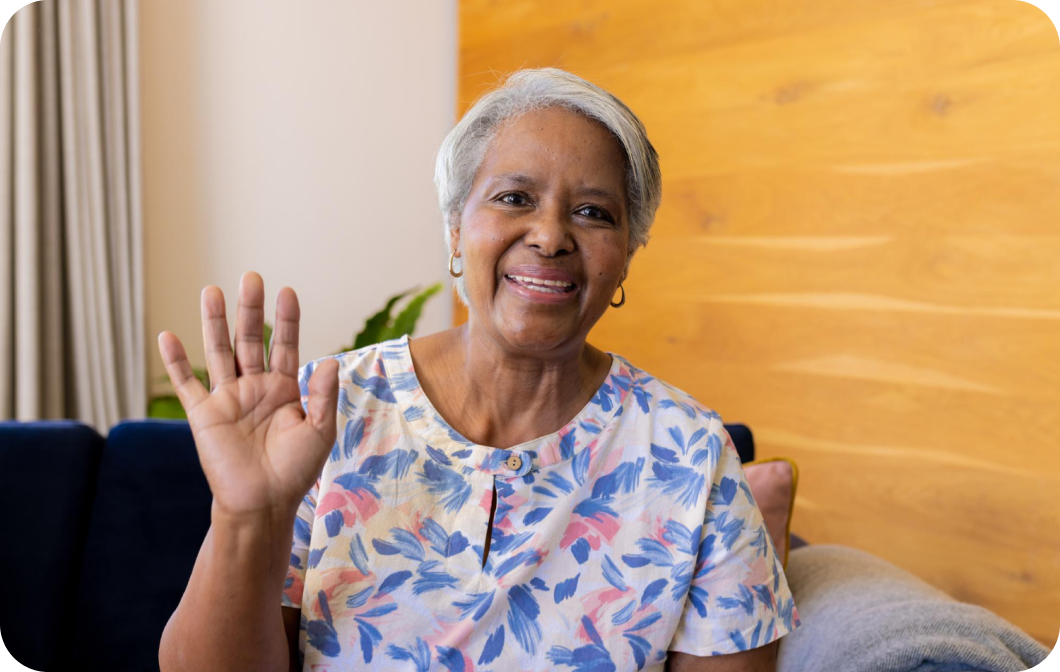 happy elderly woman waving from her couch