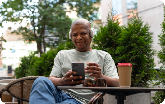man sitting outside wearing headphones holding a mobile device